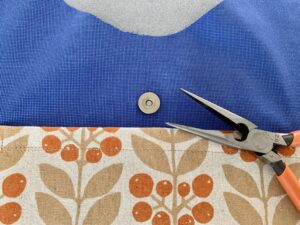 青い内布に柄物の布でポケットを縫い付け、ポケットの上にはマグネットボタンをつけたところ