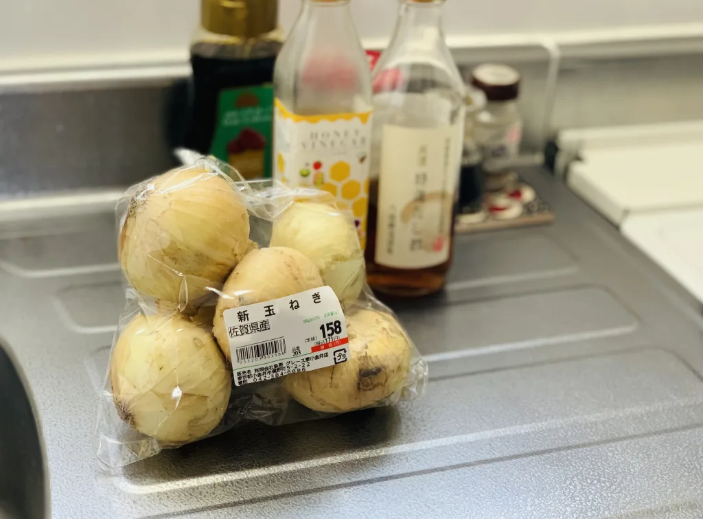 佐賀県産新玉ねぎの袋と、その後ろにハニービネガーとだし酢のボトルが写っている画像