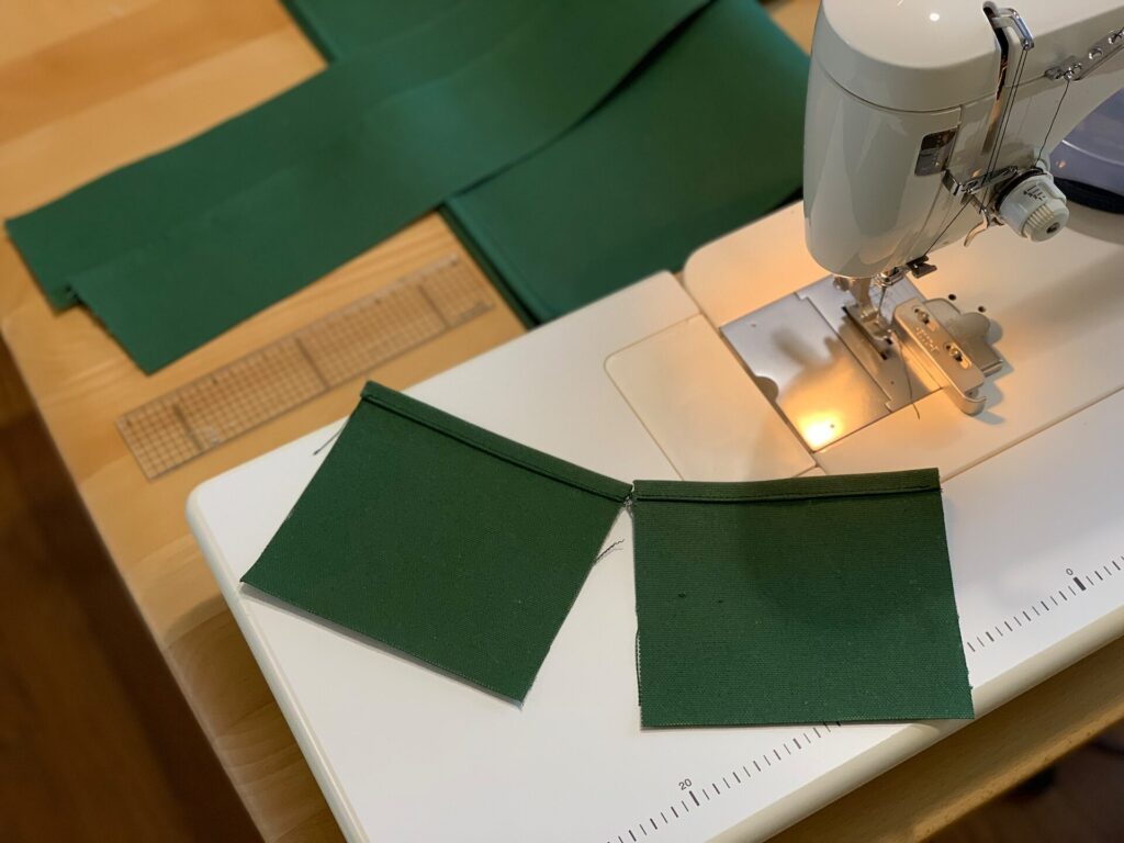 職業用ミシンのテーブル上にひろげた、緑色の帆布のポケット二点