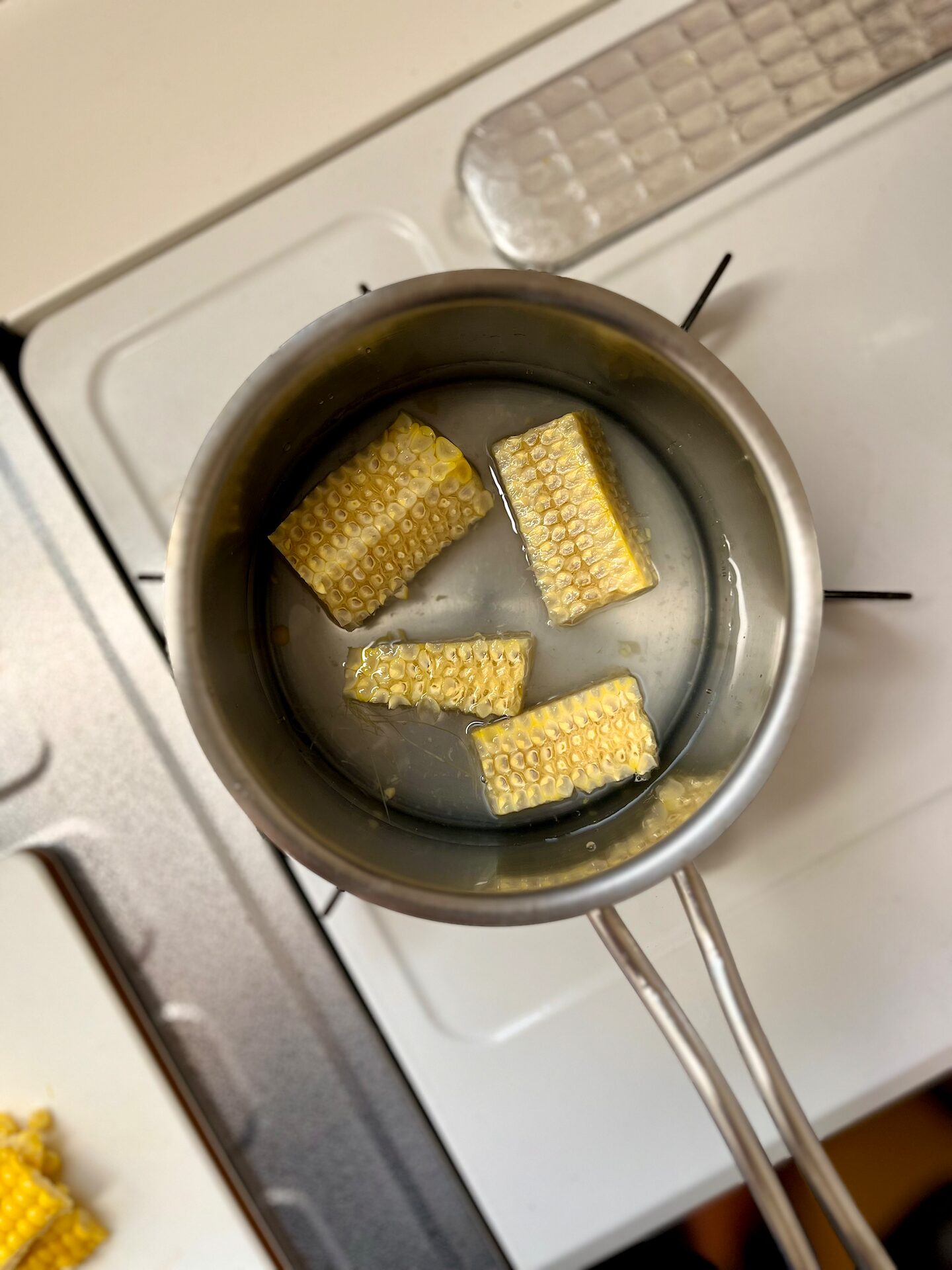 とうもろこしの芯を小鍋で水から煮て出汁をひいているところの画像